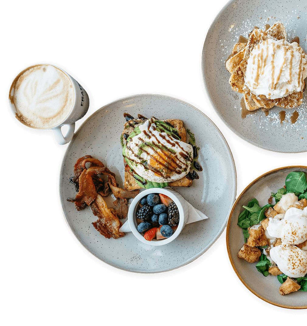 Ein Fr&uuml;hst&uuml;ckstisch mit Avocado-Toast, Waffeln, Beeren und einem Kaffee.