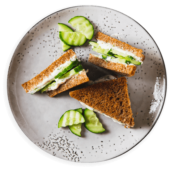 Drei Sandwiches mit Gurkenscheiben auf einem grauen Teller.