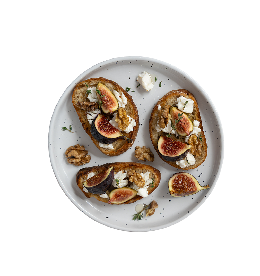 Drei belegte Brote mit Feigen, Waln&uuml;ssen und Frischk&auml;se auf einem wei&szlig;en Teller.
