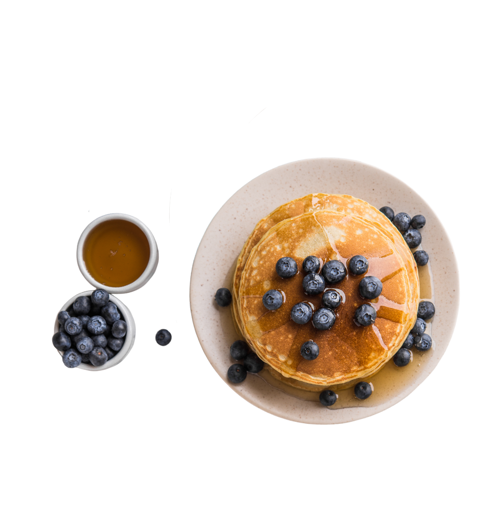 Pfannkuchenstapel mit Heidelbeeren und Ahornsirup auf einem Teller, daneben eine kleine Sch&uuml;ssel mit Sirup.